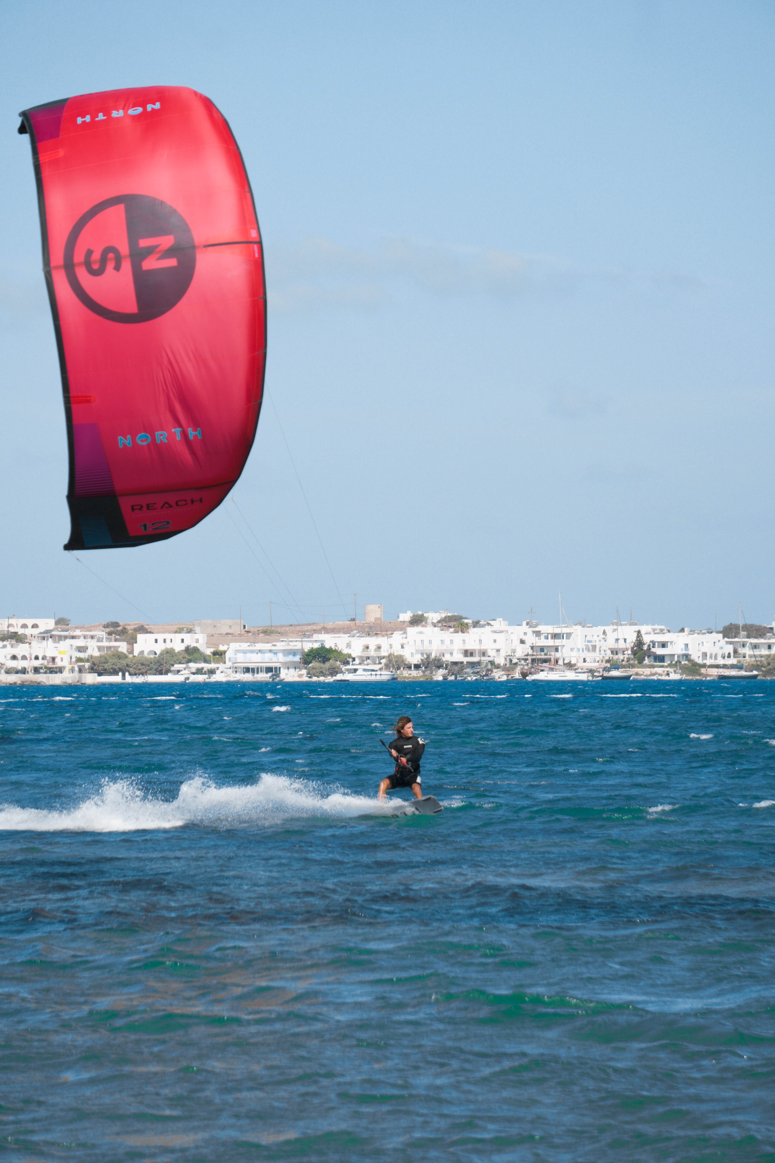 Kitesurfer with a Cyclades village behind
