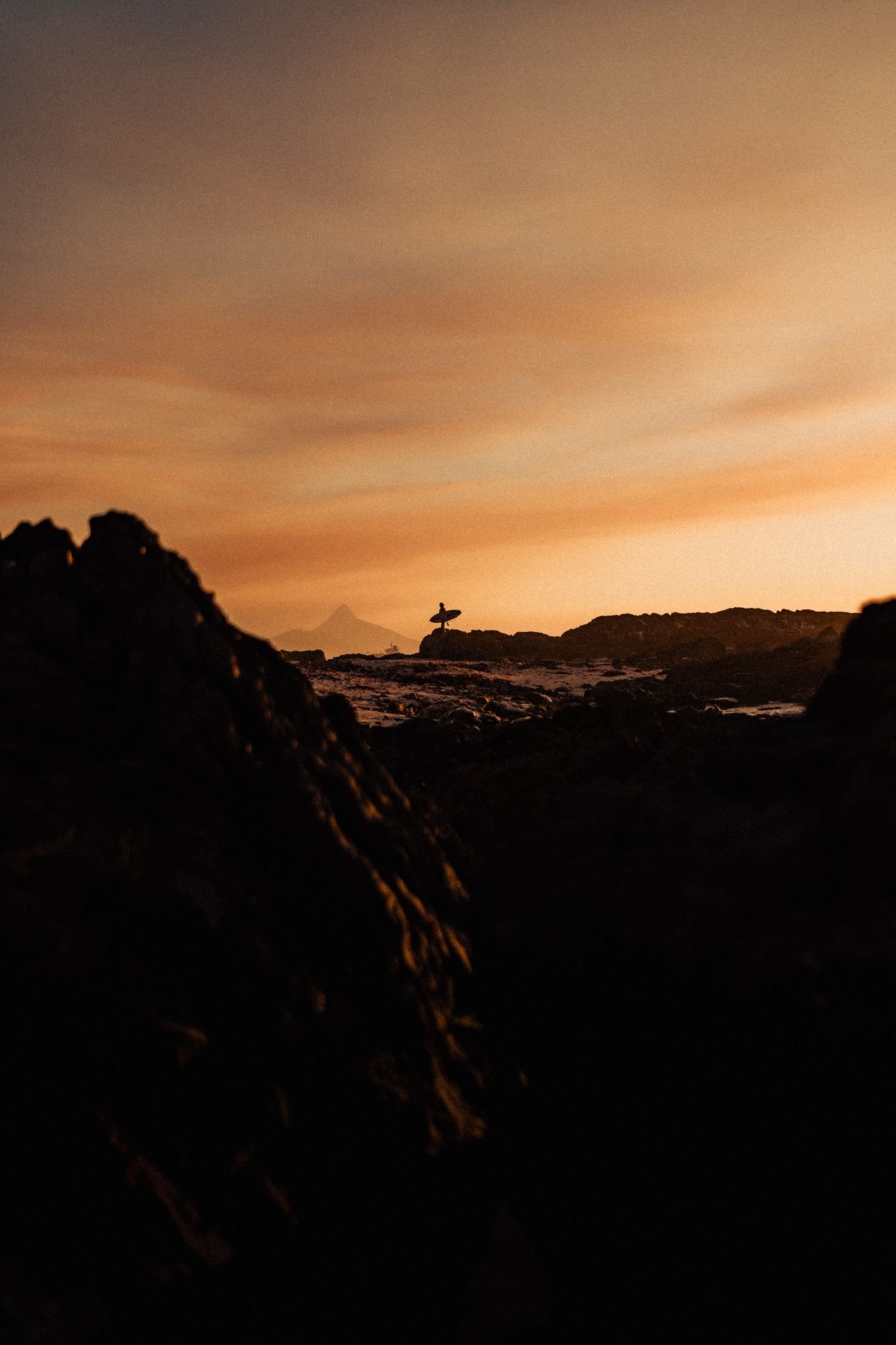 Cape Town surfer silhouette on rocks at sunset