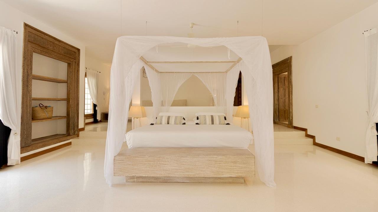 Watamu villa master bedroom with canopy bed and carved doors